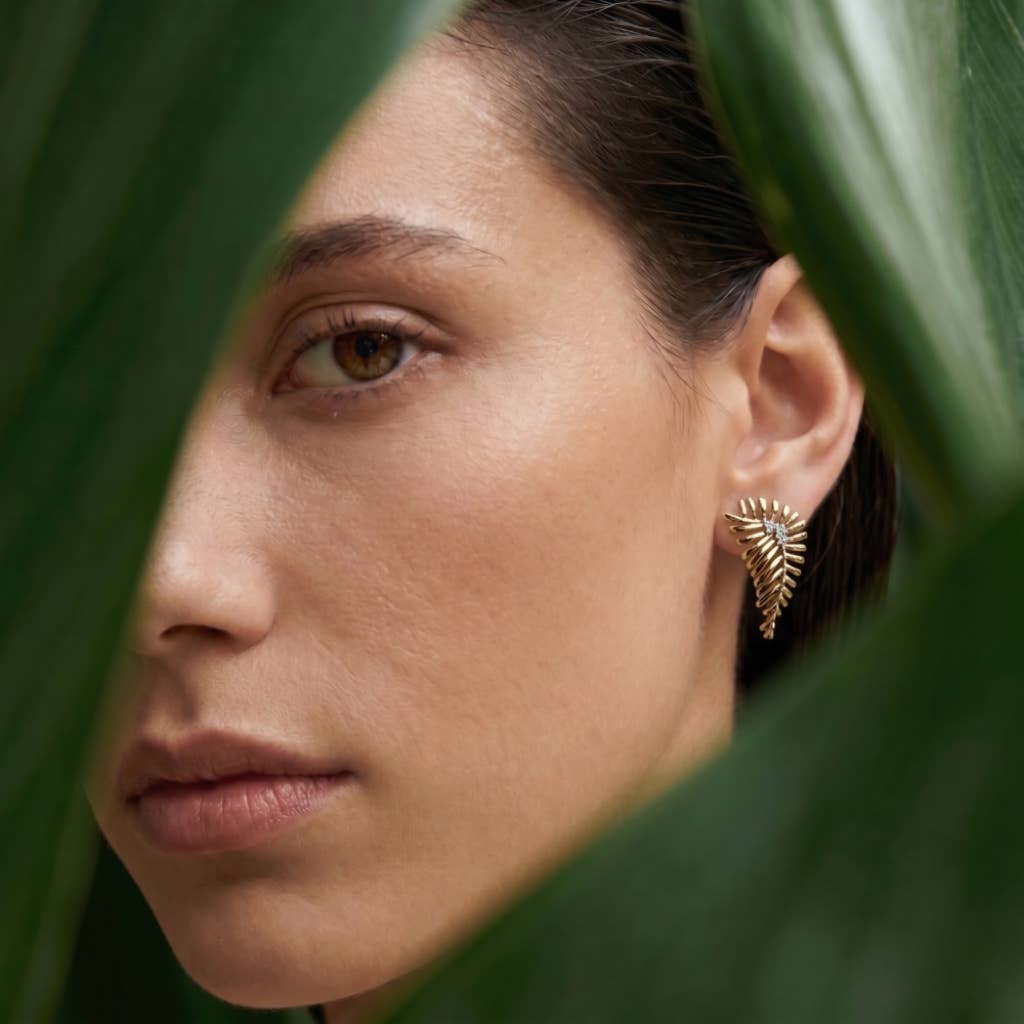 Model wearing gold fern earrings